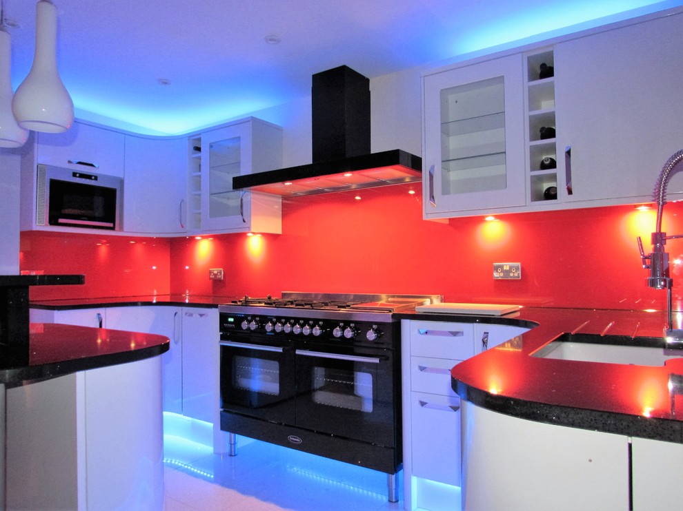 Zweizeilige, Große Moderne Wohnküche mit Waschbecken, weißen Schränken, Granit-Arbeitsplatte, Küchenrückwand in Rot, Glasrückwand, schwarzen Elektrogeräten, Marmorboden und Halbinsel in London