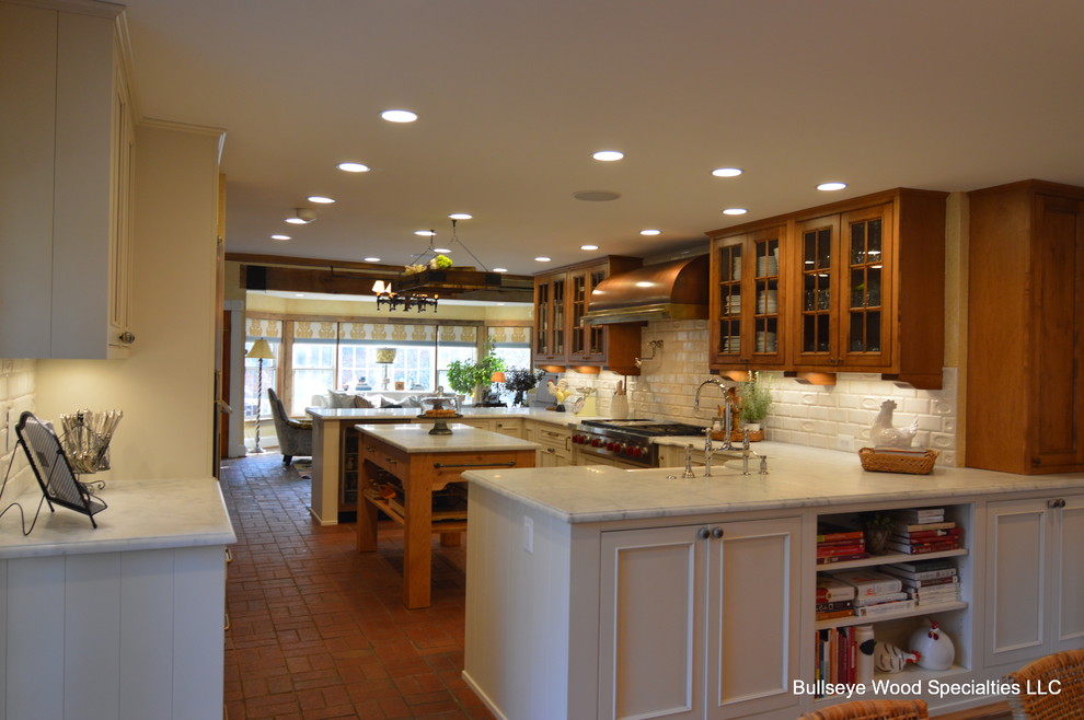 ワシントンD.C.にあるラグジュアリーな中くらいなカントリー風のおしゃれなキッチン (エプロンフロントシンク、インセット扉のキャビネット、白いキャビネット、大理石カウンター、白いキッチンパネル、サブウェイタイルのキッチンパネル、シルバーの調理設備、レンガの床) の写真