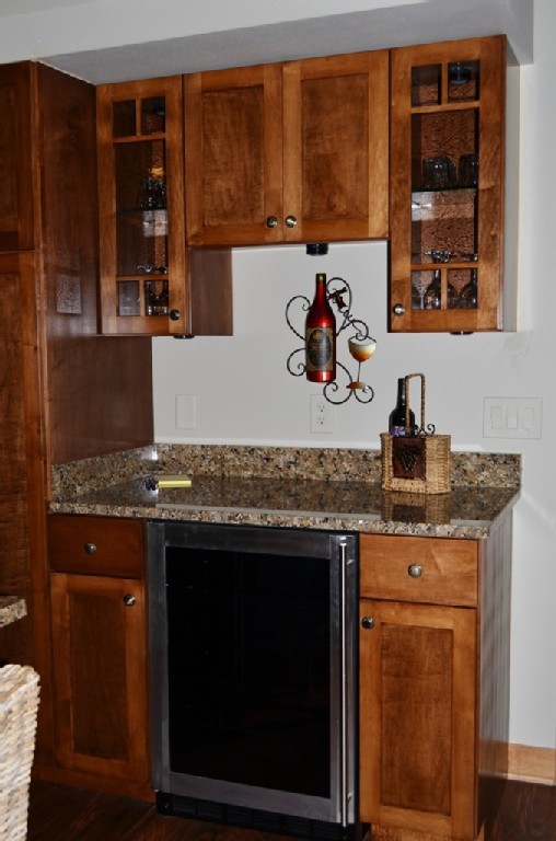 Foto di un cucina con isola centrale american style con lavello sottopiano, ante lisce, ante in legno scuro, top in granito, elettrodomestici in acciaio inossidabile e pavimento in legno massello medio