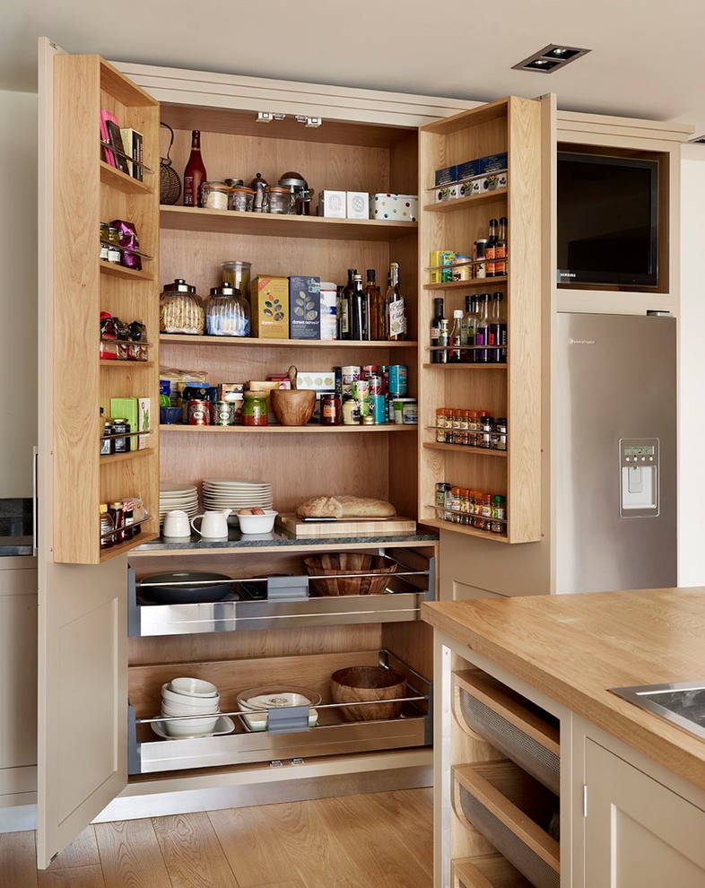 Cette photo montre une grande arrière-cuisine tendance avec un placard à porte plane, des portes de placard beiges et un plan de travail en bois.