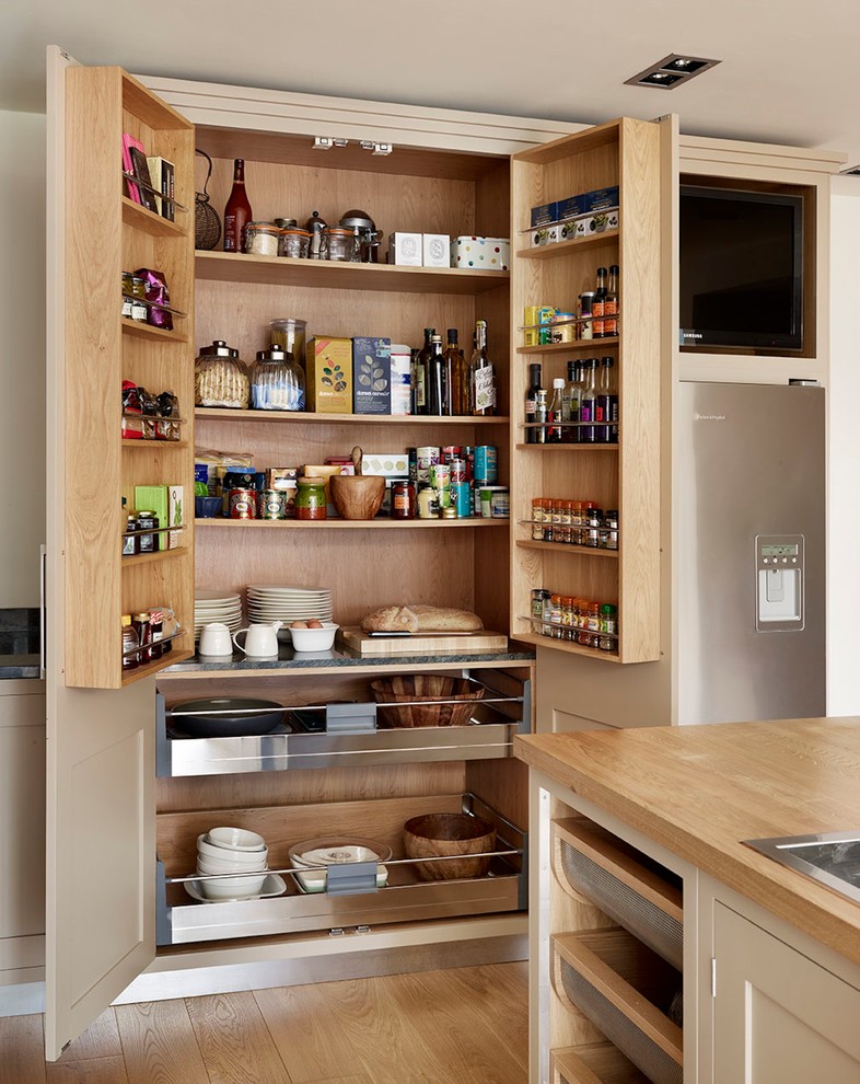 Inspiration for a large contemporary kitchen pantry remodel in London with flat-panel cabinets, beige cabinets and wood countertops
