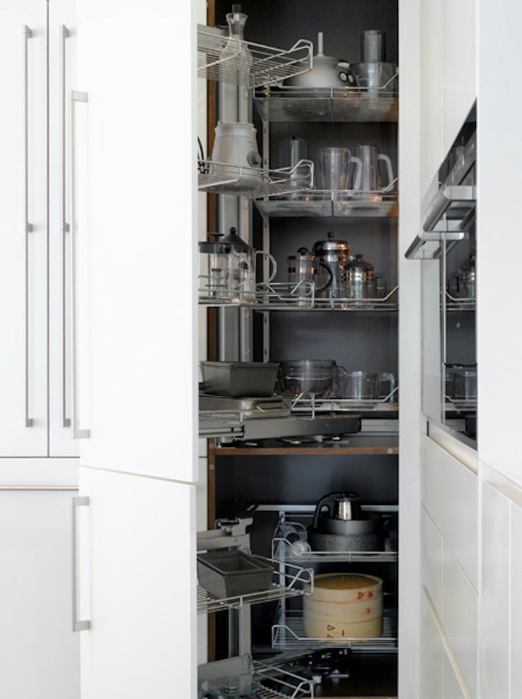 Cette image montre une grande cuisine ouverte design avec un placard à porte plane et des portes de placard blanches.