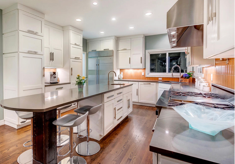 Große Moderne Küche mit Einbauwaschbecken, Schrankfronten im Shaker-Stil, weißen Schränken, Küchenrückwand in Orange, Küchengeräten aus Edelstahl, braunem Holzboden und braunem Boden in Denver