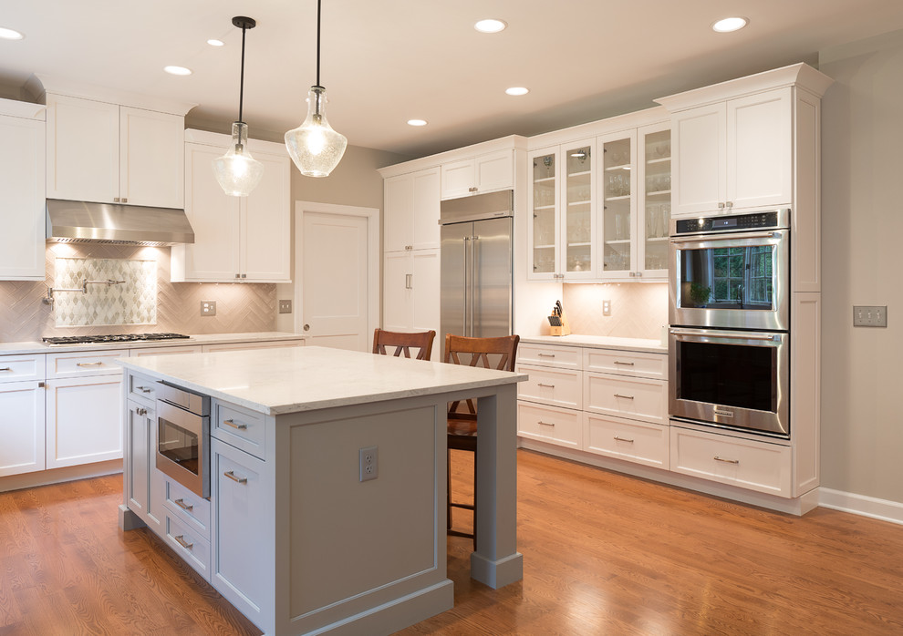 Eat-in kitchen - large transitional l-shaped medium tone wood floor and brown floor eat-in kitchen idea in DC Metro with an undermount sink, shaker cabinets, white cabinets, quartz countertops, beige backsplash, porcelain backsplash, stainless steel appliances and an island