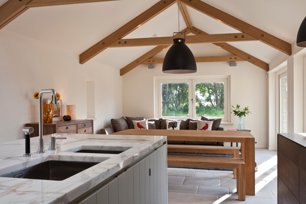 Inspiration for a large contemporary galley open plan kitchen in Gloucestershire with dark wood cabinets, marble worktops, limestone flooring, an island, an integrated sink and black appliances.