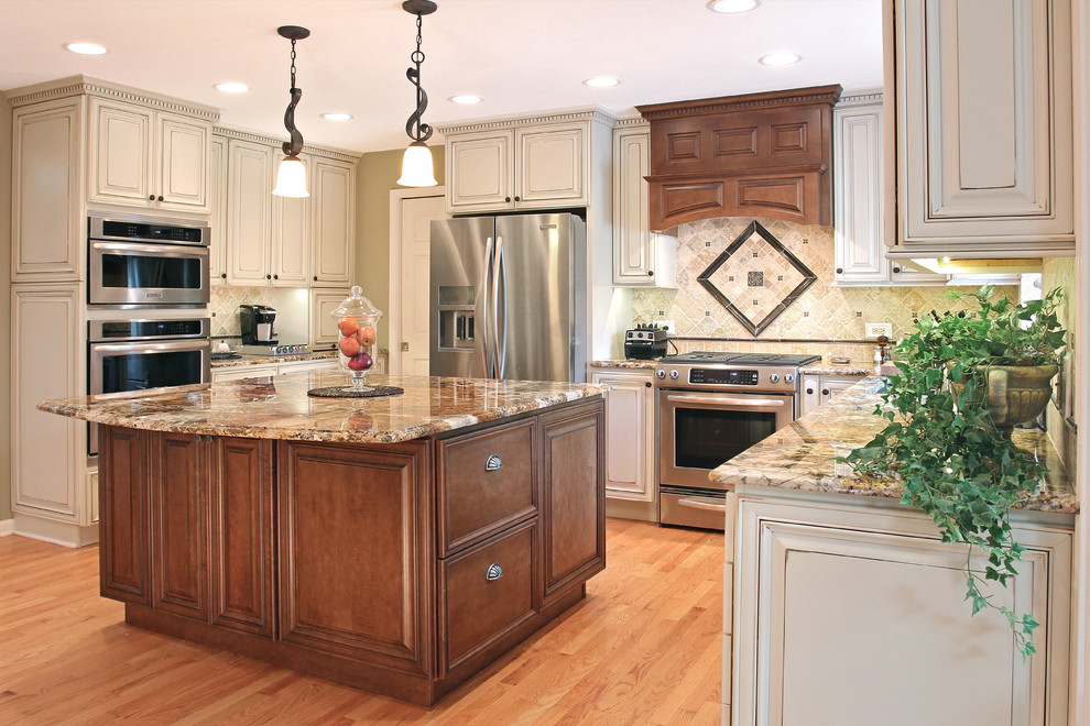 Eat-in kitchen - mid-sized traditional l-shaped light wood floor and beige floor eat-in kitchen idea in Chicago with an undermount sink, raised-panel cabinets, beige cabinets, granite countertops, beige backsplash, ceramic backsplash, stainless steel appliances and an island