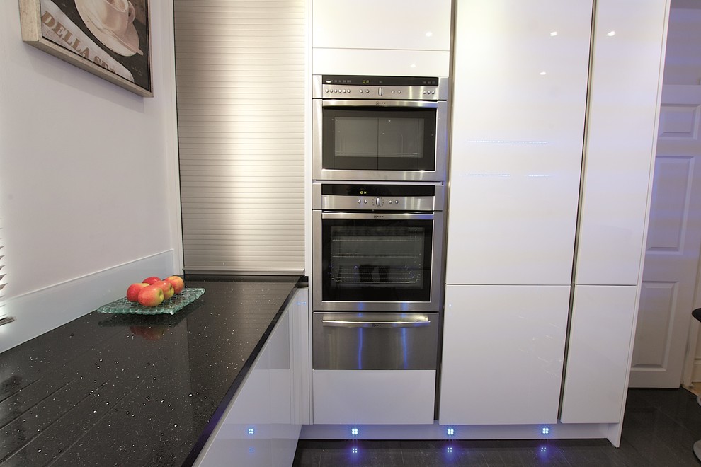 Photo of a small modern u-shaped kitchen in London with white cabinets.