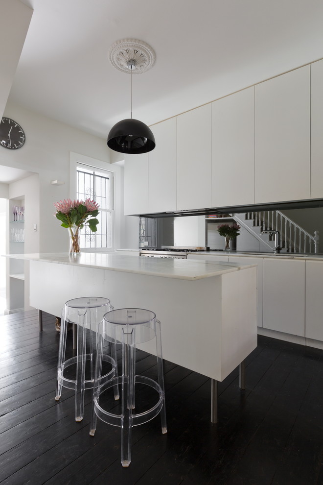 Design ideas for a large contemporary single-wall open plan kitchen in Sydney with a submerged sink, flat-panel cabinets, white cabinets, marble worktops, stainless steel appliances, dark hardwood flooring, an island, mirror splashback and black floors.