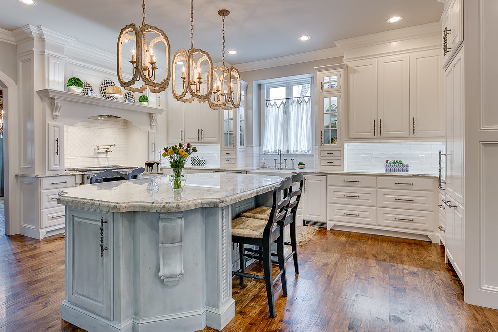 Example of a classic dark wood floor eat-in kitchen design in Oklahoma City with a farmhouse sink, shaker cabinets, white cabinets, granite countertops, white backsplash, ceramic backsplash, stainless steel appliances and an island