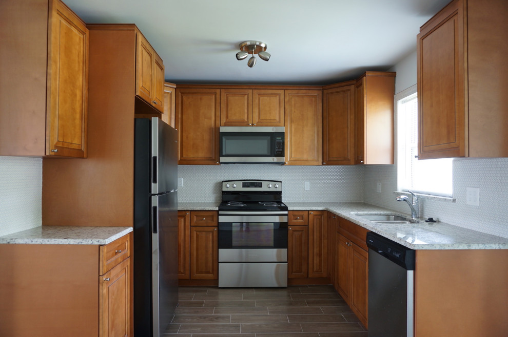 Retro inredning av ett litet grön grönt kök, med en dubbel diskho, luckor med upphöjd panel, skåp i mellenmörkt trä, granitbänkskiva, vitt stänkskydd, stänkskydd i mosaik, rostfria vitvaror, klinkergolv i porslin och brunt golv