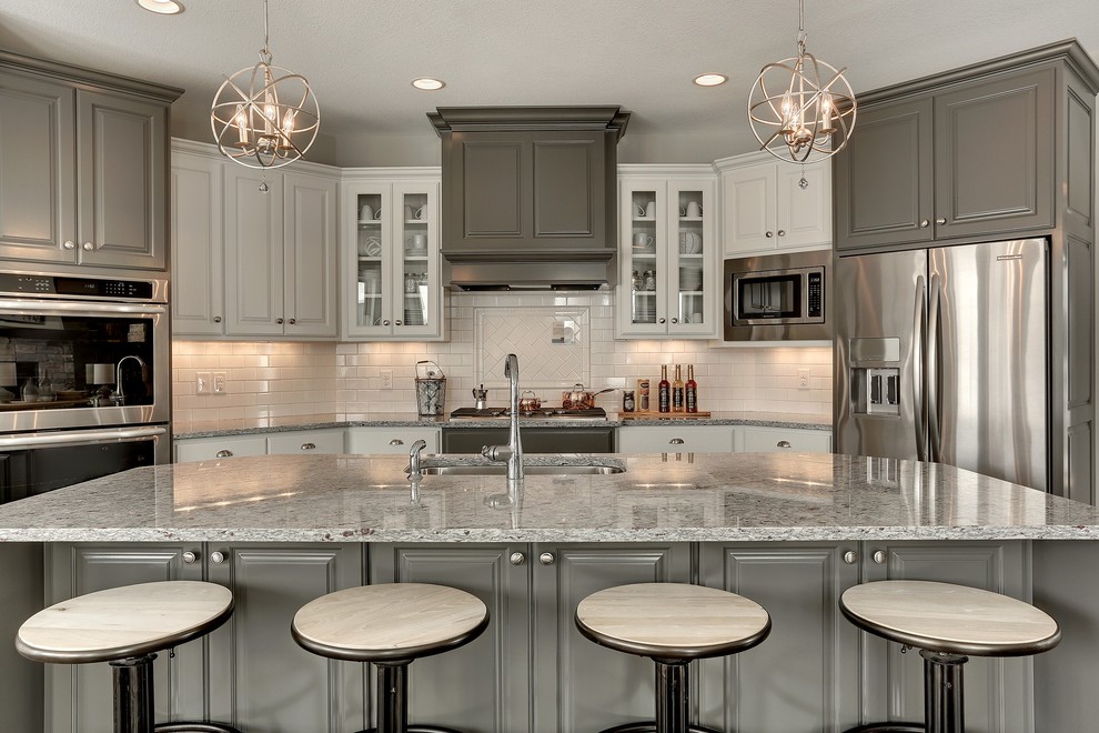 Inspiration for a large transitional u-shaped open concept kitchen remodel in Minneapolis with an undermount sink, raised-panel cabinets, gray cabinets, granite countertops, white backsplash, subway tile backsplash, stainless steel appliances and an island