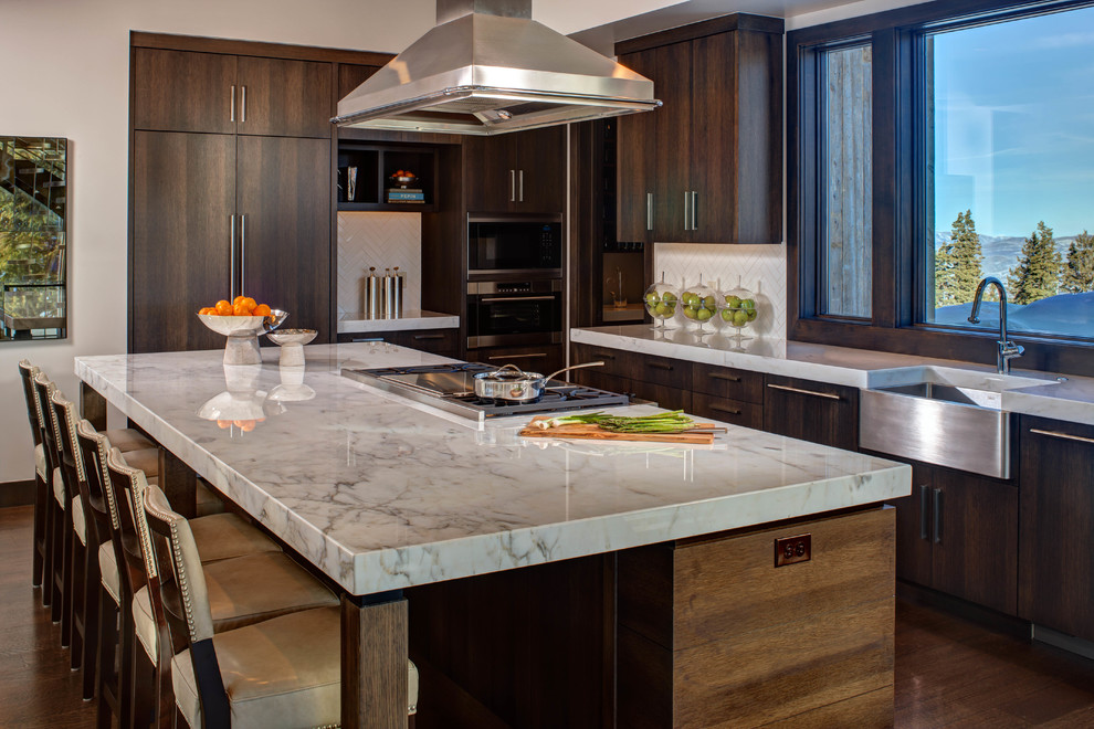 Inspiration for a large contemporary l-shaped dark wood floor and brown floor kitchen remodel in Salt Lake City with a farmhouse sink, flat-panel cabinets, dark wood cabinets, white backsplash, paneled appliances, quartzite countertops, ceramic backsplash, an island and white countertops