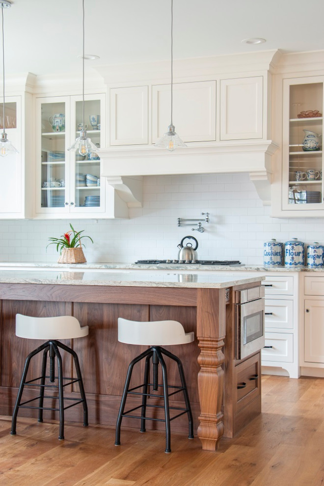 Open concept kitchen - traditional l-shaped medium tone wood floor and brown floor open concept kitchen idea in Minneapolis with a farmhouse sink, white backsplash, an island, shaker cabinets, beige cabinets, subway tile backsplash and gray countertops