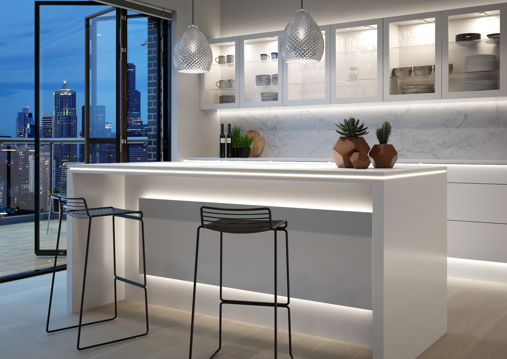 Contemporary galley kitchen/diner in Other with flat-panel cabinets, white cabinets, white splashback, light hardwood flooring, an island, beige floors and white worktops.