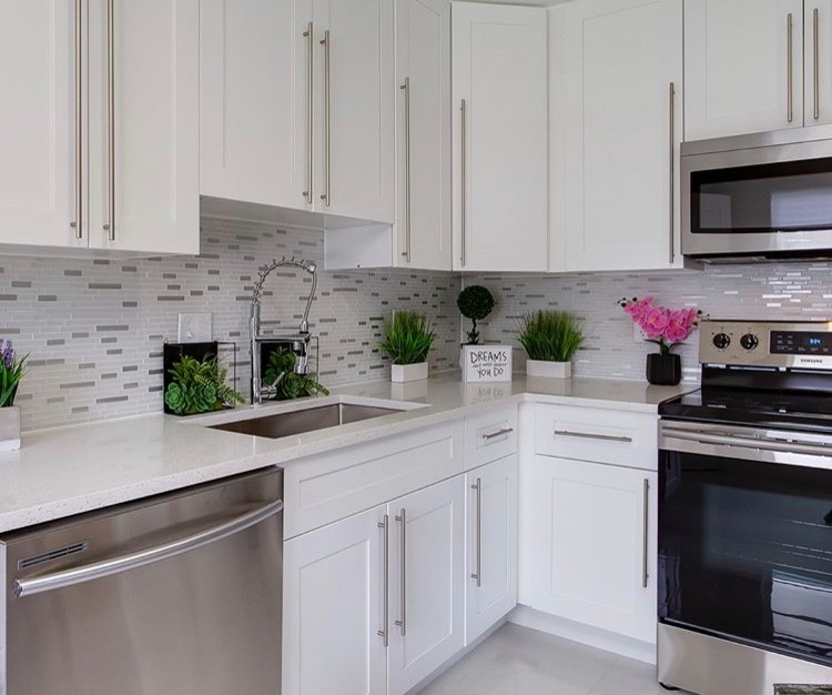 Modern inredning av ett litet vit vitt kök, med en undermonterad diskho, skåp i shakerstil, vita skåp, bänkskiva i kvarts, flerfärgad stänkskydd, stänkskydd i stickkakel, rostfria vitvaror, klinkergolv i porslin och vitt golv