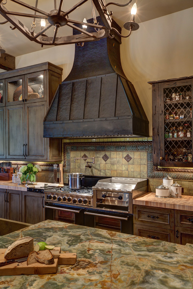 Immagine di un'ampia cucina mediterranea chiusa con ante con bugna sagomata, ante in legno bruno, paraspruzzi beige, paraspruzzi con piastrelle in ceramica, pavimento in travertino e pavimento marrone