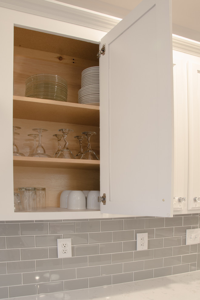 ローリーにあるお手頃価格の中くらいなトランジショナルスタイルのおしゃれなキッチン (レイズドパネル扉のキャビネット、白いキャビネット、珪岩カウンター、グレーのキッチンパネル、ガラスタイルのキッチンパネル、淡色無垢フローリング) の写真