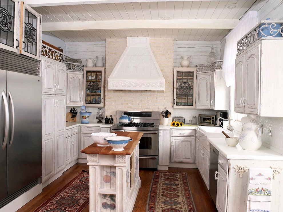 Foto de cocinas en U tradicional cerrado con electrodomésticos de acero inoxidable, fregadero sobremueble, puertas de armario blancas y salpicadero blanco