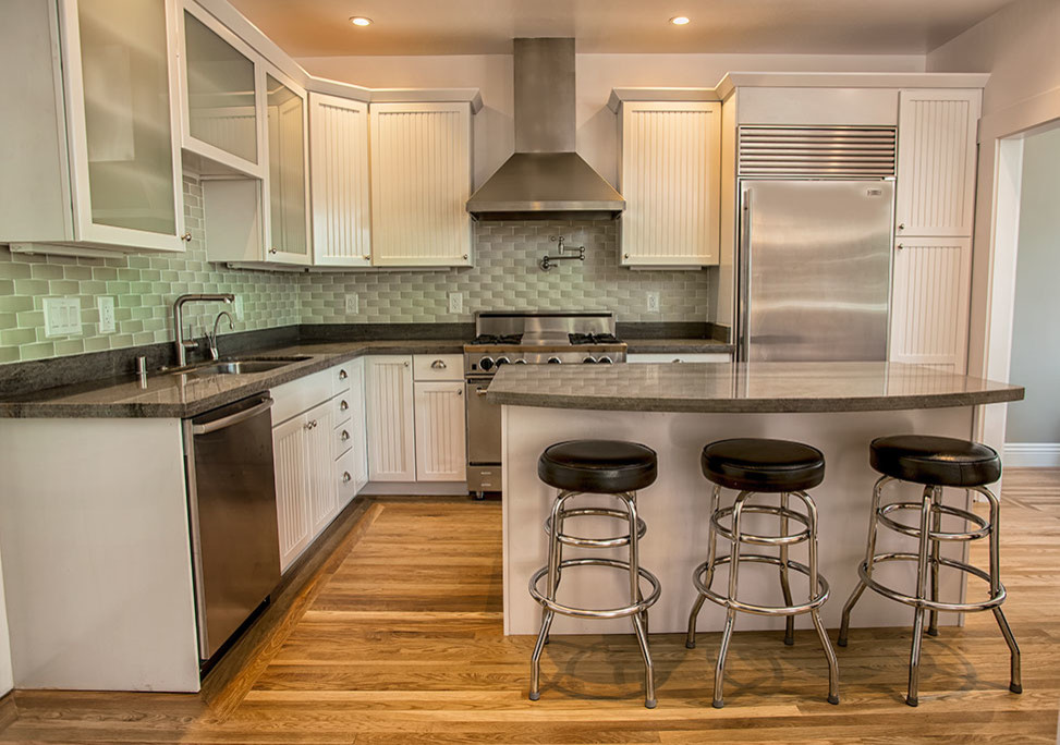 Inspiration for a mid-sized timeless l-shaped medium tone wood floor eat-in kitchen remodel in San Francisco with an undermount sink, beaded inset cabinets, white cabinets, granite countertops, green backsplash, ceramic backsplash, stainless steel appliances and an island