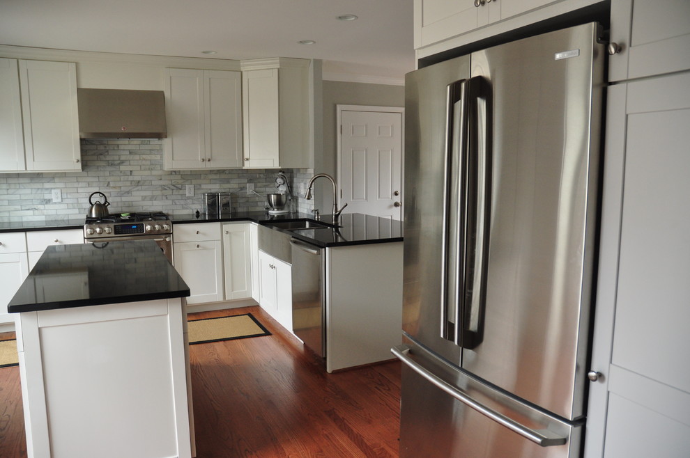 Modelo de cocina minimalista grande con puertas de armario blancas, encimera de cuarzo compacto, electrodomésticos de acero inoxidable y una isla