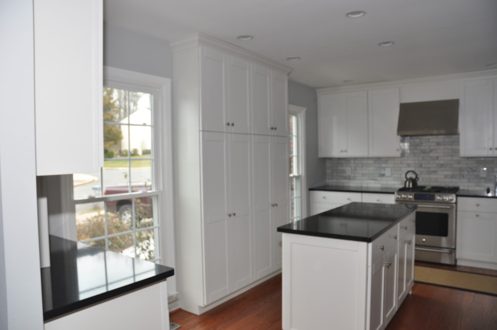 Immagine di una grande cucina minimalista con ante bianche, top in quarzo composito e elettrodomestici in acciaio inossidabile