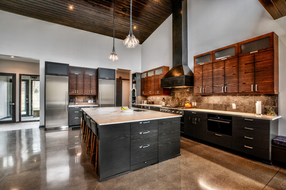 Modern inredning av ett stort kök, med en undermonterad diskho, släta luckor, skåp i mörkt trä, bänkskiva i kvarts, grått stänkskydd, stänkskydd i stenkakel, rostfria vitvaror, betonggolv, en köksö och grått golv