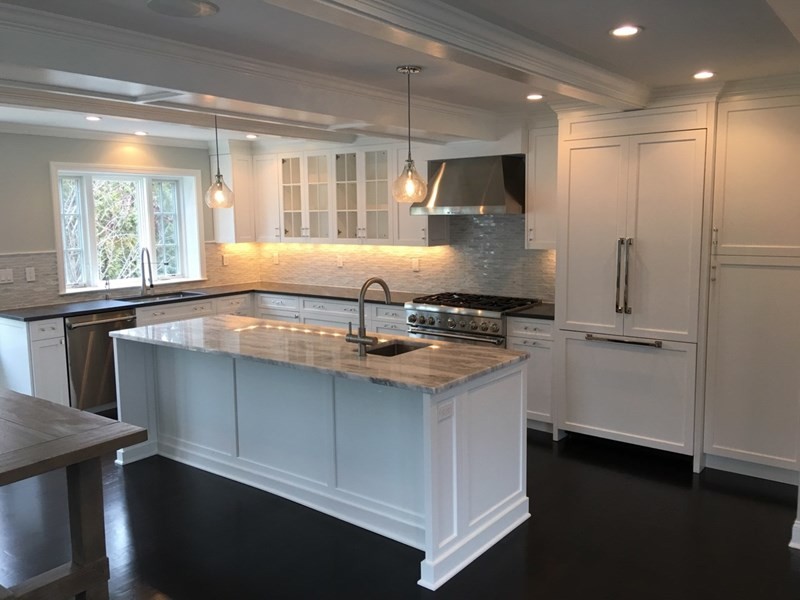 This is an example of a medium sized classic u-shaped kitchen/diner in New York with a submerged sink, shaker cabinets, white cabinets, quartz worktops, white splashback, glass tiled splashback, stainless steel appliances, dark hardwood flooring and an island.