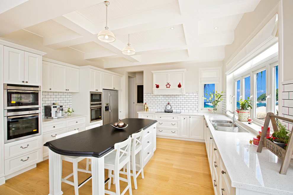 Eat-in kitchen - huge traditional u-shaped light wood floor eat-in kitchen idea in Sydney with a drop-in sink, shaker cabinets, white cabinets, quartz countertops, white backsplash, subway tile backsplash, stainless steel appliances and an island