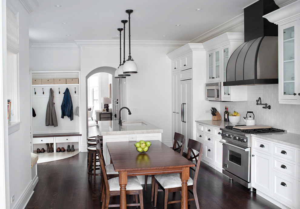 Large elegant single-wall dark wood floor eat-in kitchen photo in Chicago with a farmhouse sink, glass-front cabinets, white cabinets, quartzite countertops, white backsplash, subway tile backsplash, stainless steel appliances and an island