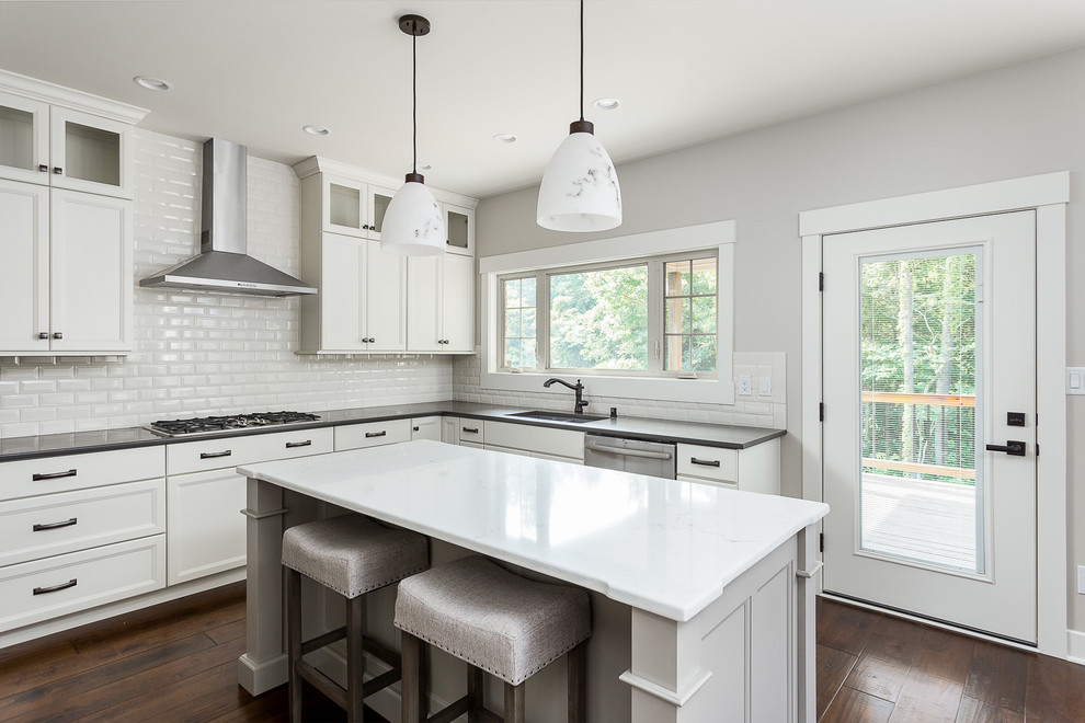 Foto de cocina de estilo americano con encimera de cuarcita, salpicadero blanco, electrodomésticos de acero inoxidable y suelo de madera en tonos medios