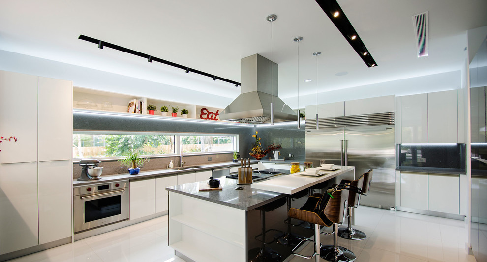 Photo of a medium sized modern kitchen in Miami with a double-bowl sink, flat-panel cabinets, grey cabinets, quartz worktops, grey splashback, stone slab splashback, stainless steel appliances, porcelain flooring and an island.