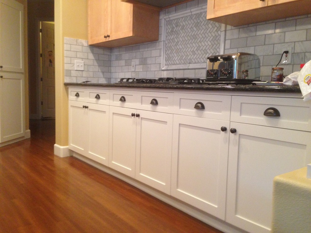 Esempio di una cucina lineare chic di medie dimensioni con ante con riquadro incassato, ante in legno chiaro, top in granito, paraspruzzi grigio, elettrodomestici neri e pavimento in legno massello medio