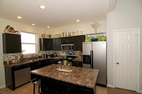 Exempel på ett modernt l-kök, med en nedsänkt diskho, luckor med infälld panel, svarta skåp, laminatbänkskiva, flerfärgad stänkskydd, stänkskydd i mosaik, rostfria vitvaror, linoleumgolv och en köksö