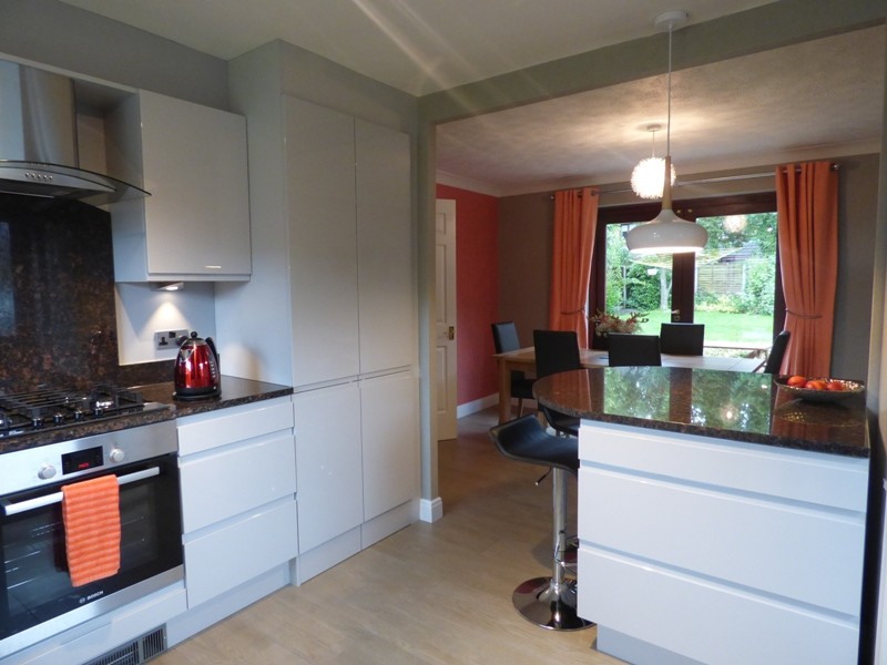 Photo of a medium sized contemporary u-shaped kitchen/diner in Other with a double-bowl sink, white cabinets, granite worktops, brown splashback, stainless steel appliances, light hardwood flooring and a breakfast bar.