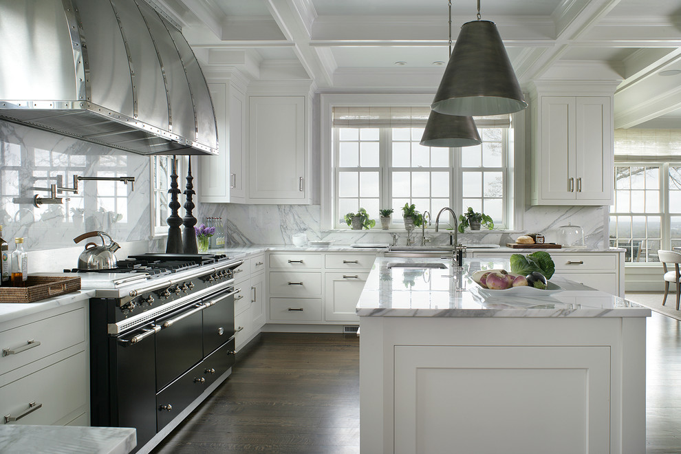 Inspiration for a large traditional open plan kitchen in New York with a submerged sink, flat-panel cabinets, white cabinets, marble worktops, white splashback, marble splashback, black appliances, dark hardwood flooring, brown floors and an island.