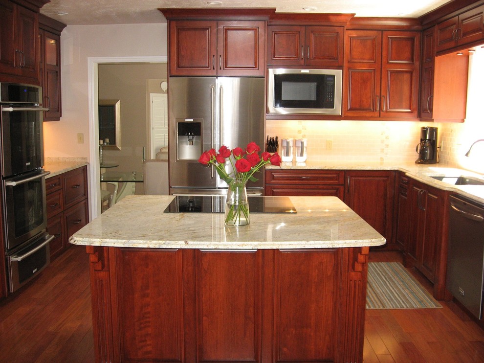This is an example of a traditional u-shaped kitchen in Salt Lake City with a submerged sink, raised-panel cabinets, dark wood cabinets, granite worktops, beige splashback, stone tiled splashback, stainless steel appliances, medium hardwood flooring and an island.