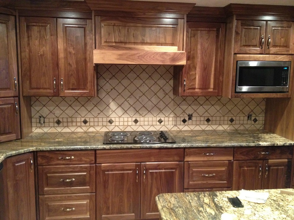 Exempel på ett klassiskt kök, med luckor med upphöjd panel, skåp i mellenmörkt trä, granitbänkskiva, beige stänkskydd, stänkskydd i stenkakel, rostfria vitvaror och en köksö