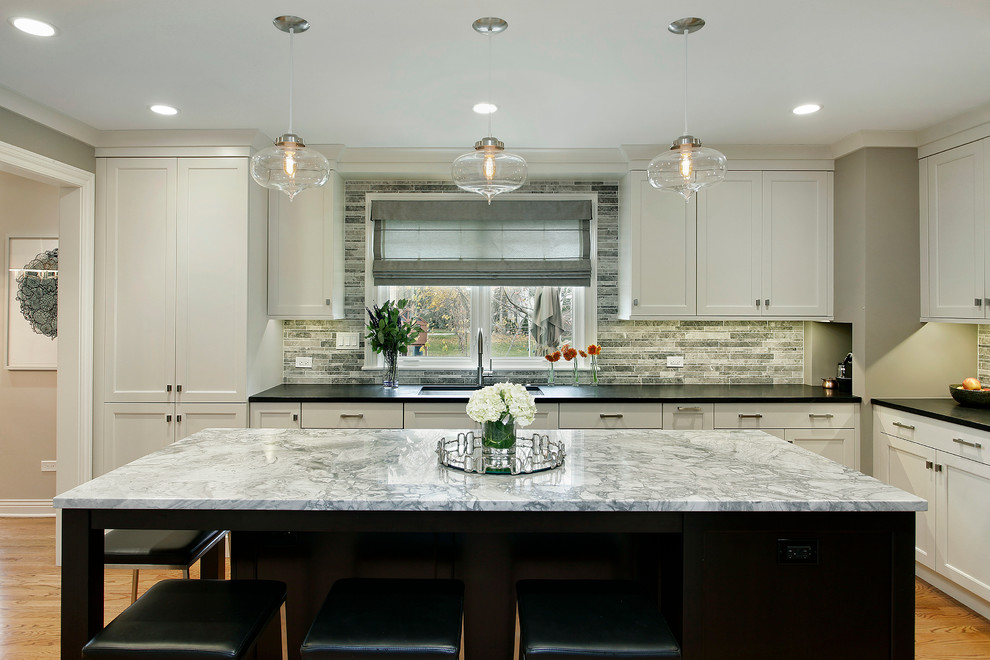 Classic l-shaped kitchen in Chicago with a submerged sink, shaker cabinets, white cabinets, multi-coloured splashback, medium hardwood flooring and an island.