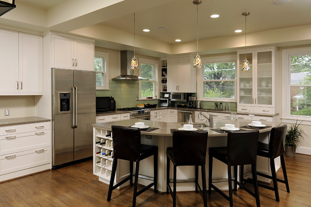 ワシントンD.C.にあるコンテンポラリースタイルのおしゃれなL型キッチン (ガラスタイルのキッチンパネル、シルバーの調理設備、クオーツストーンカウンター、緑のキッチンパネル、落し込みパネル扉のキャビネット、白いキャビネット) の写真