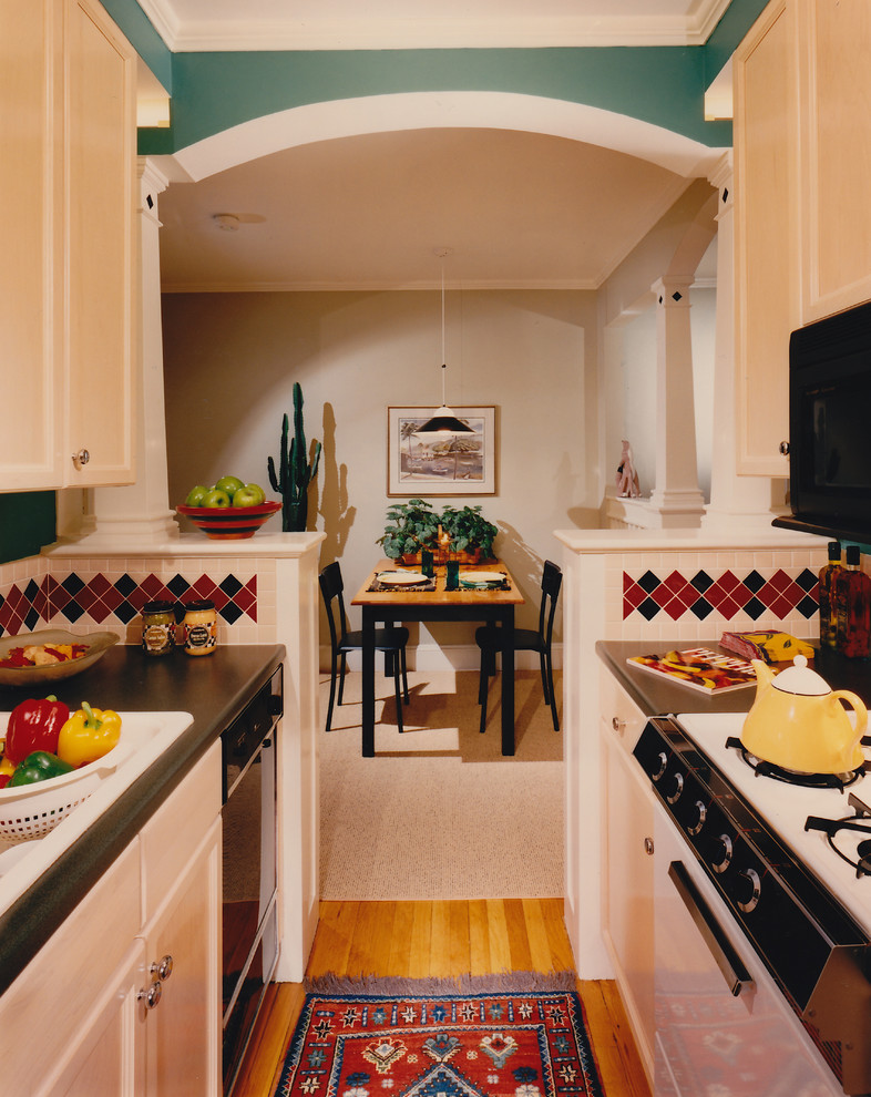 Photo of a small classic galley enclosed kitchen in Boston with a built-in sink, shaker cabinets, beige cabinets, laminate countertops, beige splashback, ceramic splashback, black appliances, medium hardwood flooring and no island.
