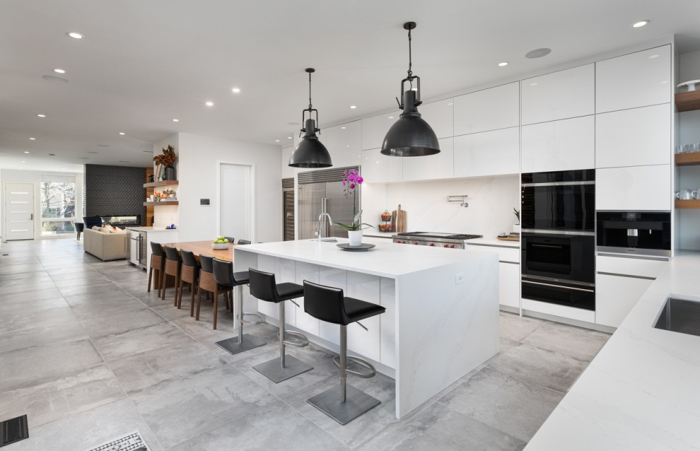 Example of a large minimalist u-shaped gray floor and porcelain tile eat-in kitchen design with flat-panel cabinets, white cabinets, quartz countertops, white backsplash, quartz backsplash, stainless steel appliances, an island, white countertops and an undermount sink
