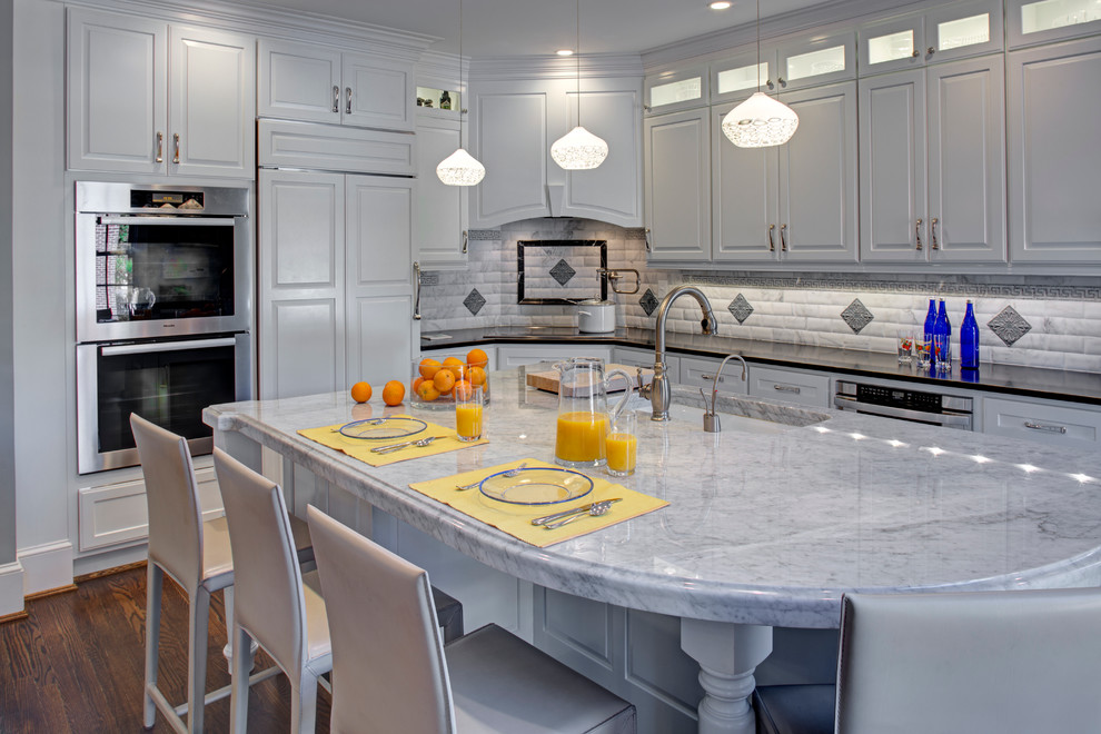 Eat-in kitchen - large traditional l-shaped medium tone wood floor eat-in kitchen idea in DC Metro with an undermount sink, white cabinets, granite countertops, gray backsplash, subway tile backsplash, stainless steel appliances and an island