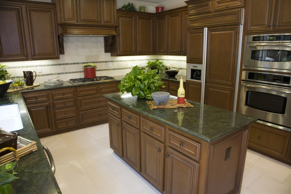 Exempel på ett klassiskt kök, med en undermonterad diskho, luckor med upphöjd panel, skåp i mellenmörkt trä, granitbänkskiva, beige stänkskydd, stänkskydd i stenkakel och rostfria vitvaror