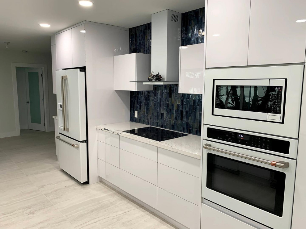 Foto di una piccola cucina parallela moderna con lavello sottopiano, ante lisce, ante bianche, top in quarzo composito, paraspruzzi blu, paraspruzzi con piastrelle di vetro, elettrodomestici bianchi e top bianco