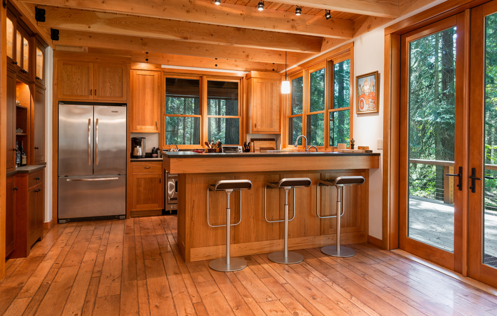 Open concept kitchen - mid-sized rustic galley medium tone wood floor and brown floor open concept kitchen idea in Other with shaker cabinets, medium tone wood cabinets, window backsplash, stainless steel appliances, a peninsula and black countertops