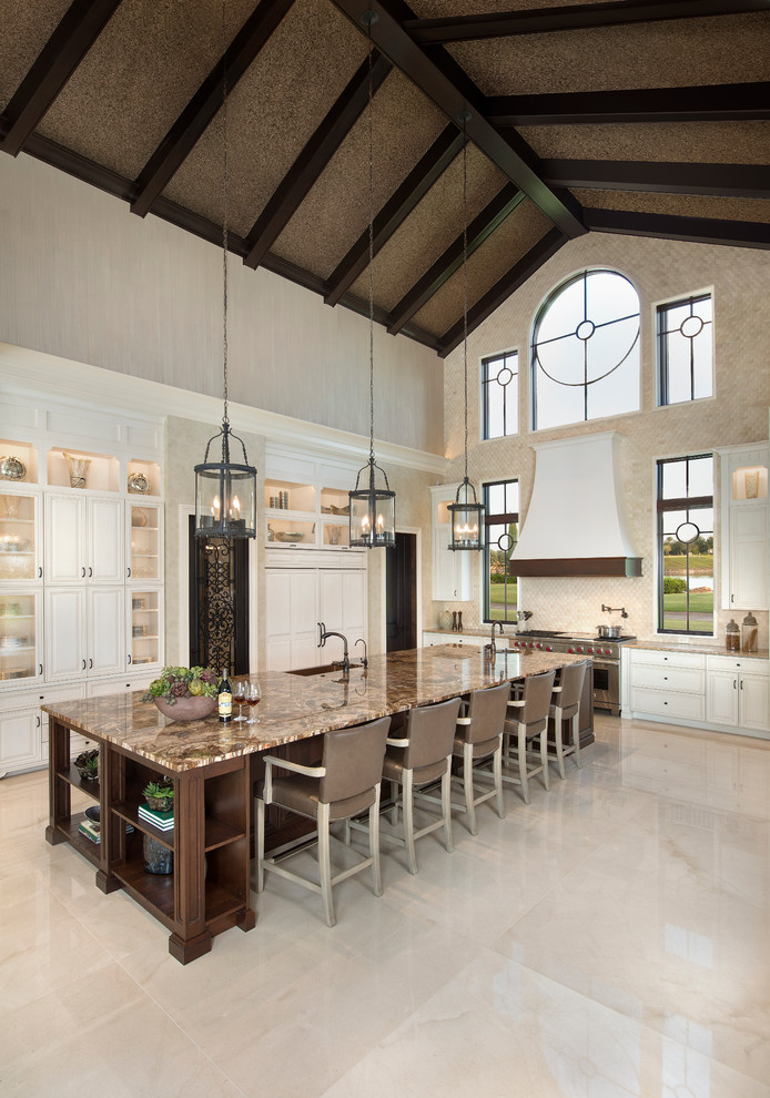 Inspiration for a large transitional l-shaped open concept kitchen remodel in Miami with a farmhouse sink, glass-front cabinets, white cabinets, stone tile backsplash, stainless steel appliances and an island