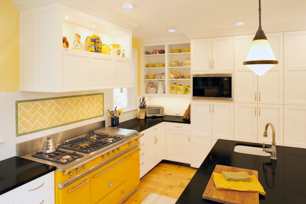 Example of a large classic light wood floor kitchen pantry design in New York with an undermount sink, shaker cabinets, white cabinets, quartz countertops, white backsplash, subway tile backsplash, stainless steel appliances and an island