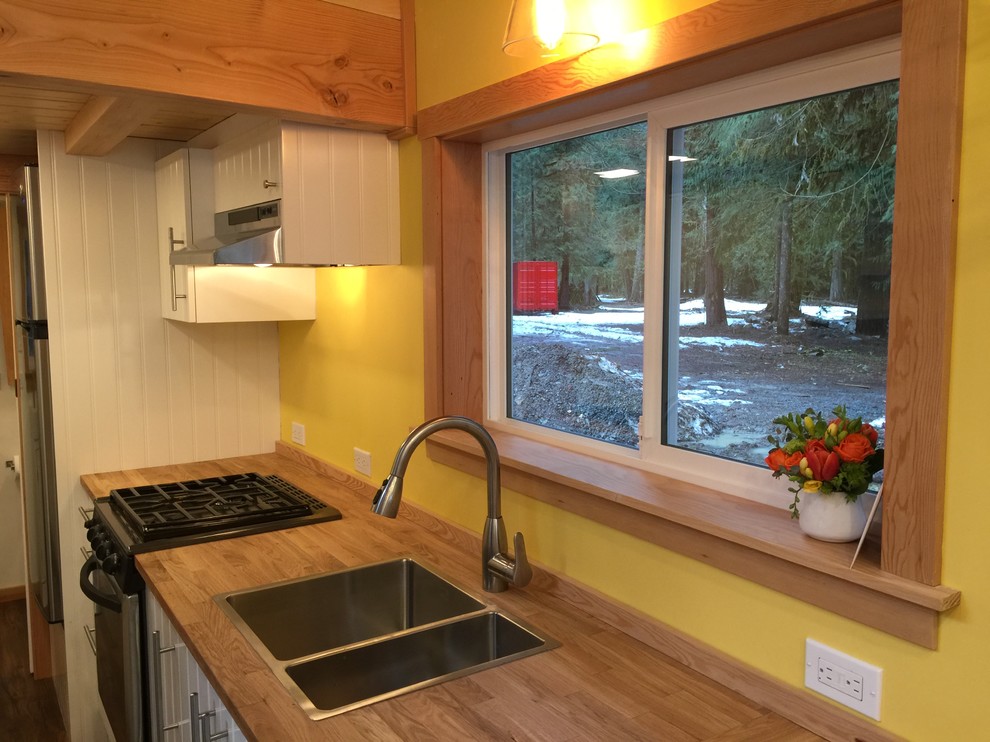 Example of a small mountain style l-shaped vinyl floor kitchen pantry design in Vancouver with a double-bowl sink, flat-panel cabinets, white cabinets, wood countertops, yellow backsplash, stainless steel appliances and an island