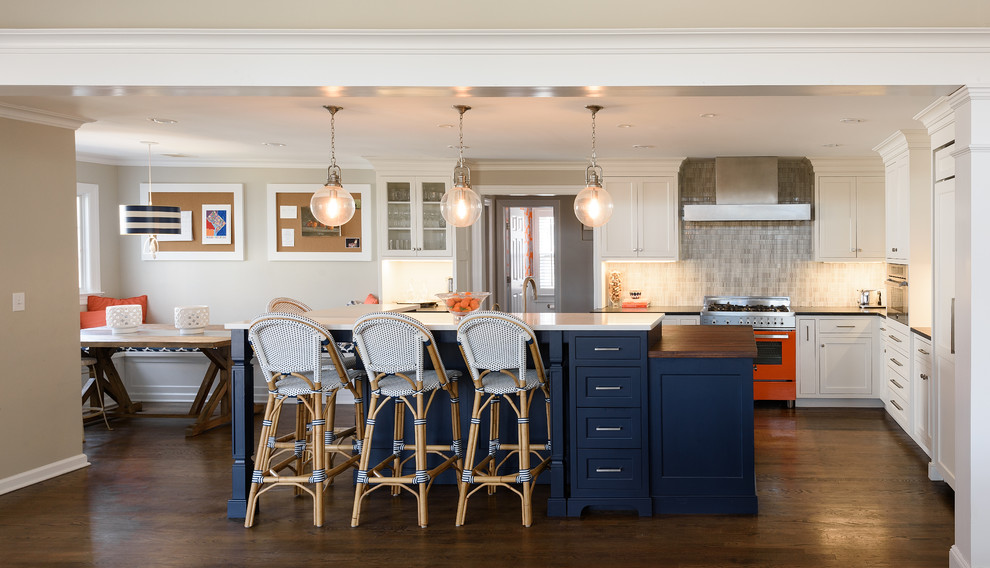 This is an example of a large traditional l-shaped open plan kitchen in New York with a built-in sink, shaker cabinets, white cabinets, wood worktops, blue splashback, ceramic splashback, coloured appliances, dark hardwood flooring, an island and brown floors.
