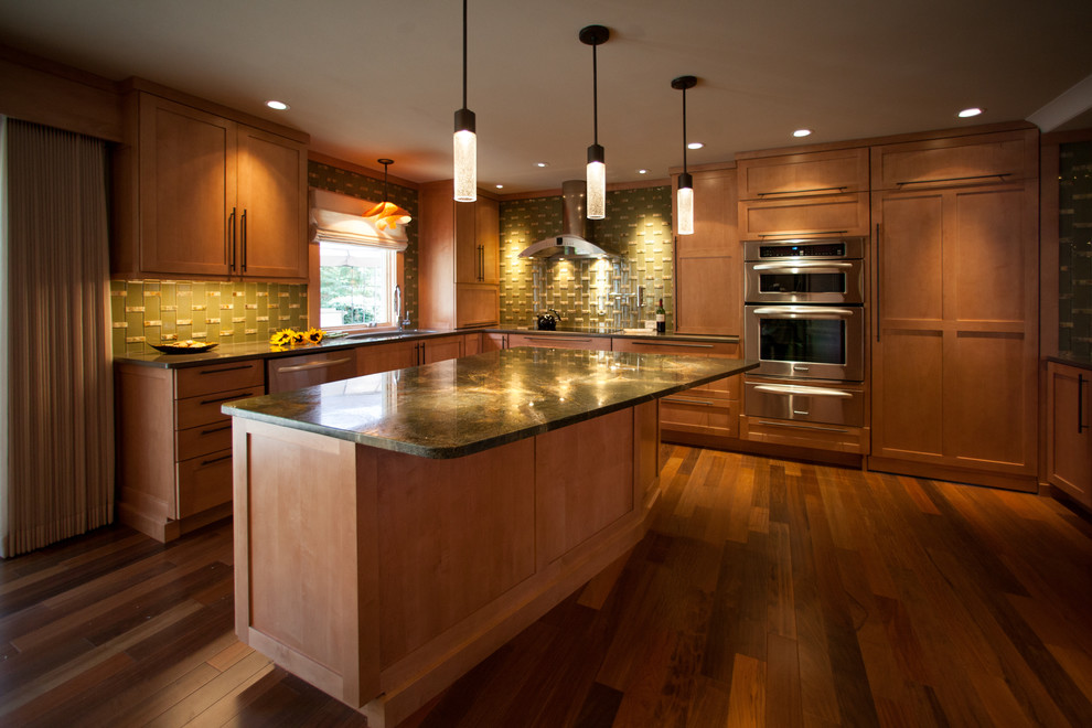 Modern inredning av ett stort kök och matrum, med en enkel diskho, granitbänkskiva, grönt stänkskydd, stänkskydd i glaskakel, rostfria vitvaror, mellanmörkt trägolv och en köksö